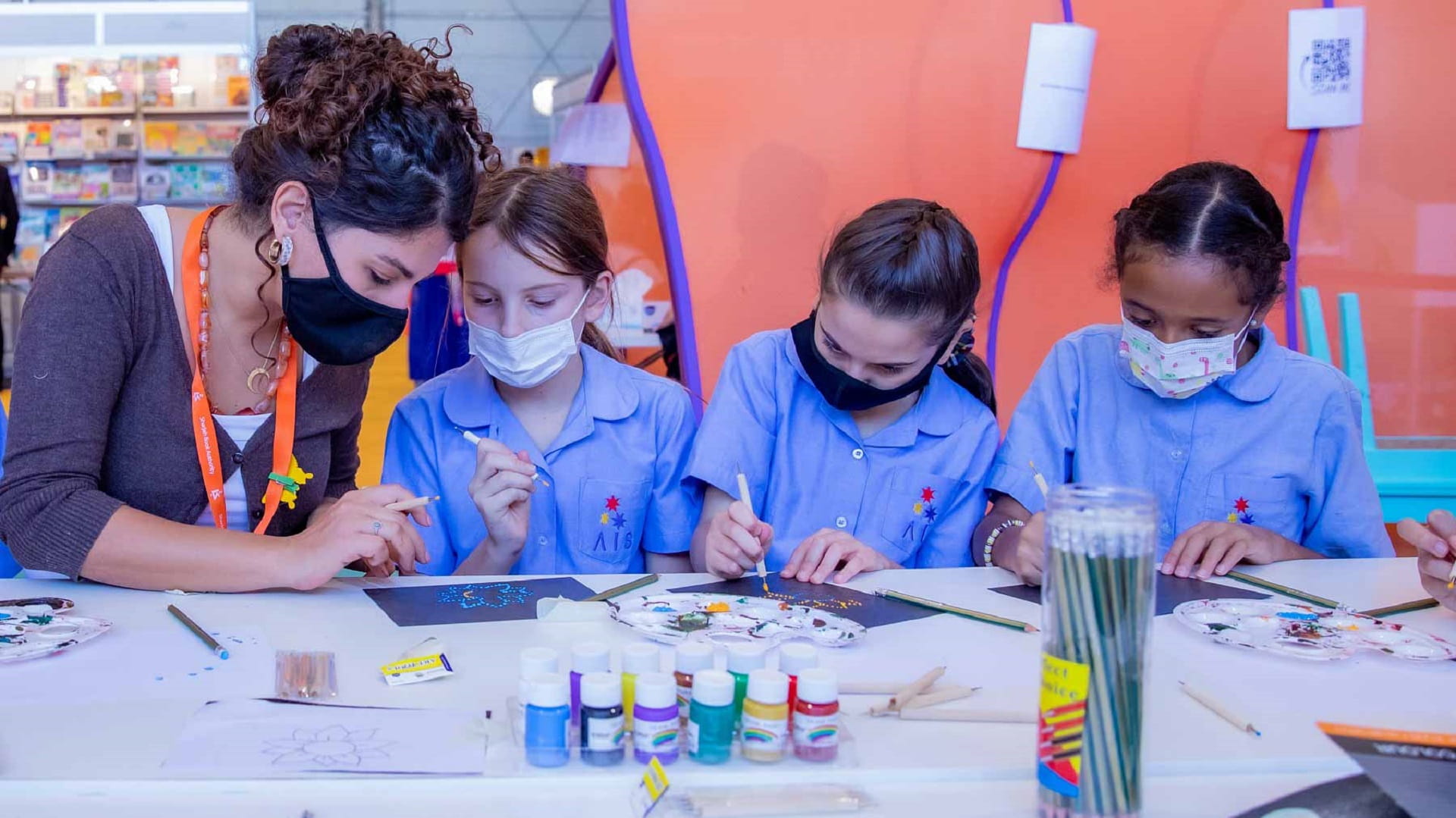 Image for the title: Children learn technique of painting using coloured dots at SIBF 