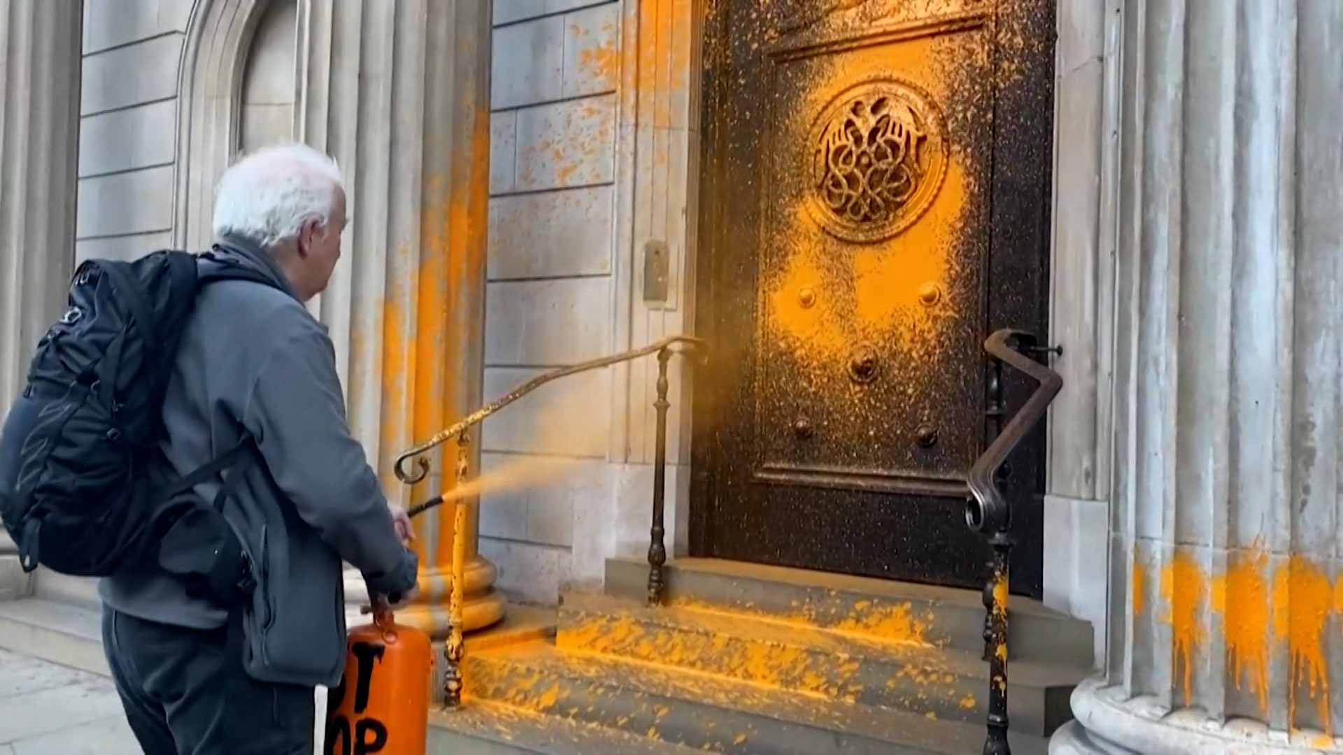 Image for the title: Climate activists spray-paint London landmarks orange 